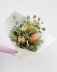 A small sized seasonal native arrangement featuring 2 banksias, a protea, gum and wattle foliage. This arrangement is wrapped in white paper.