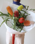 A Woman holds a bouquet of five assorted stems of Australian Native Banksia Flowers.