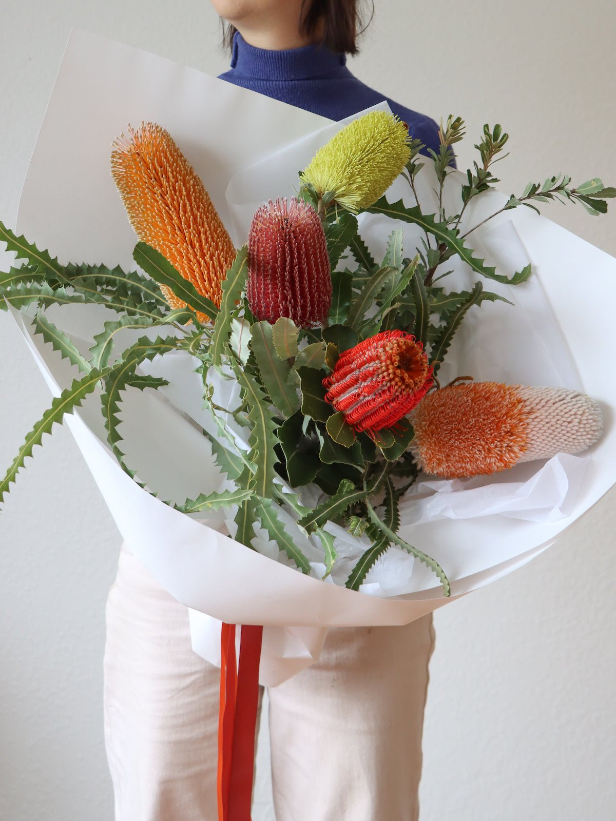 A Woman holds a bouquet of five assorted stems of Australian Native Banksia Flowers.