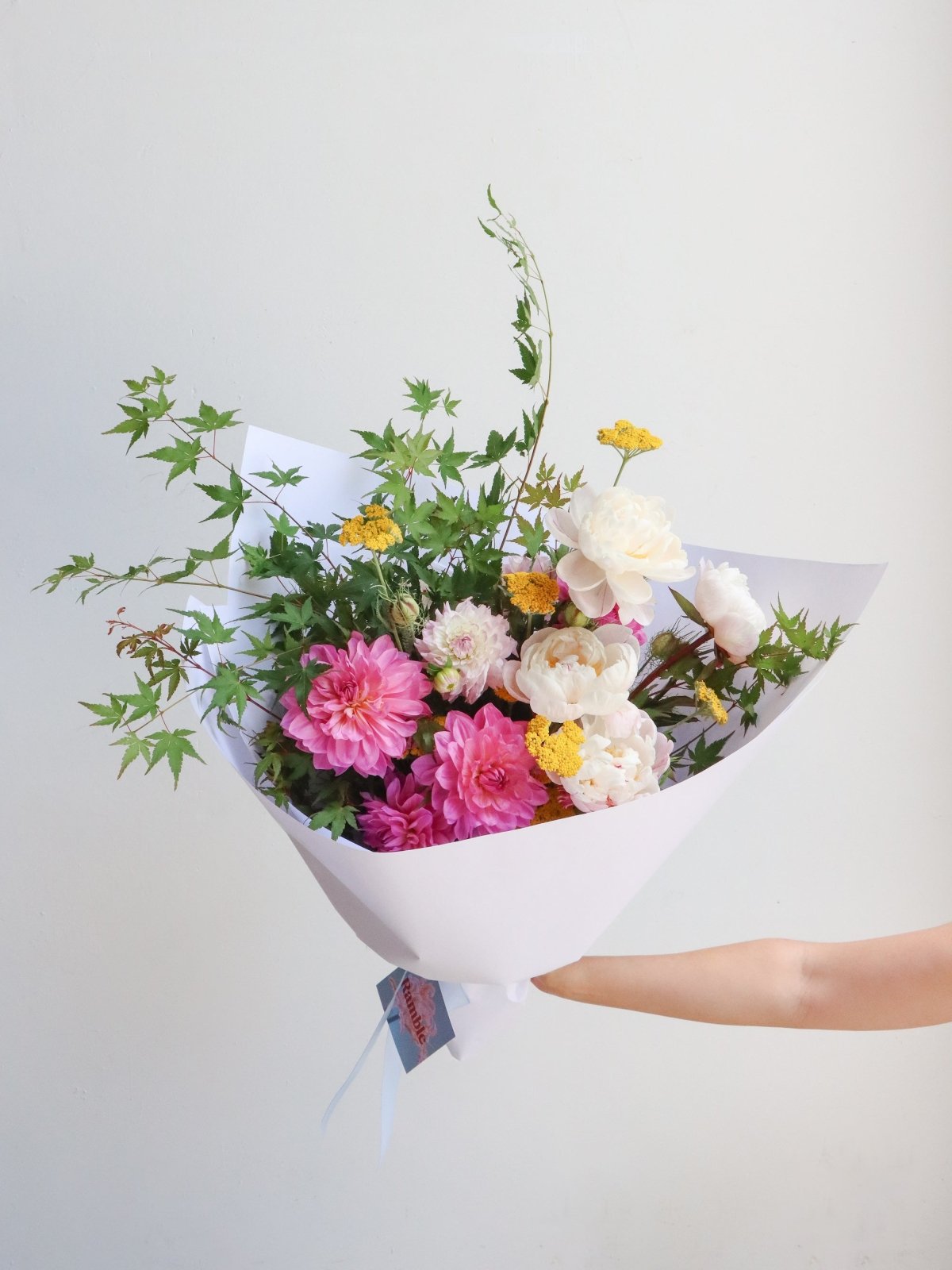 A bouquet of seasonal flowers, wrapped in white paper. 